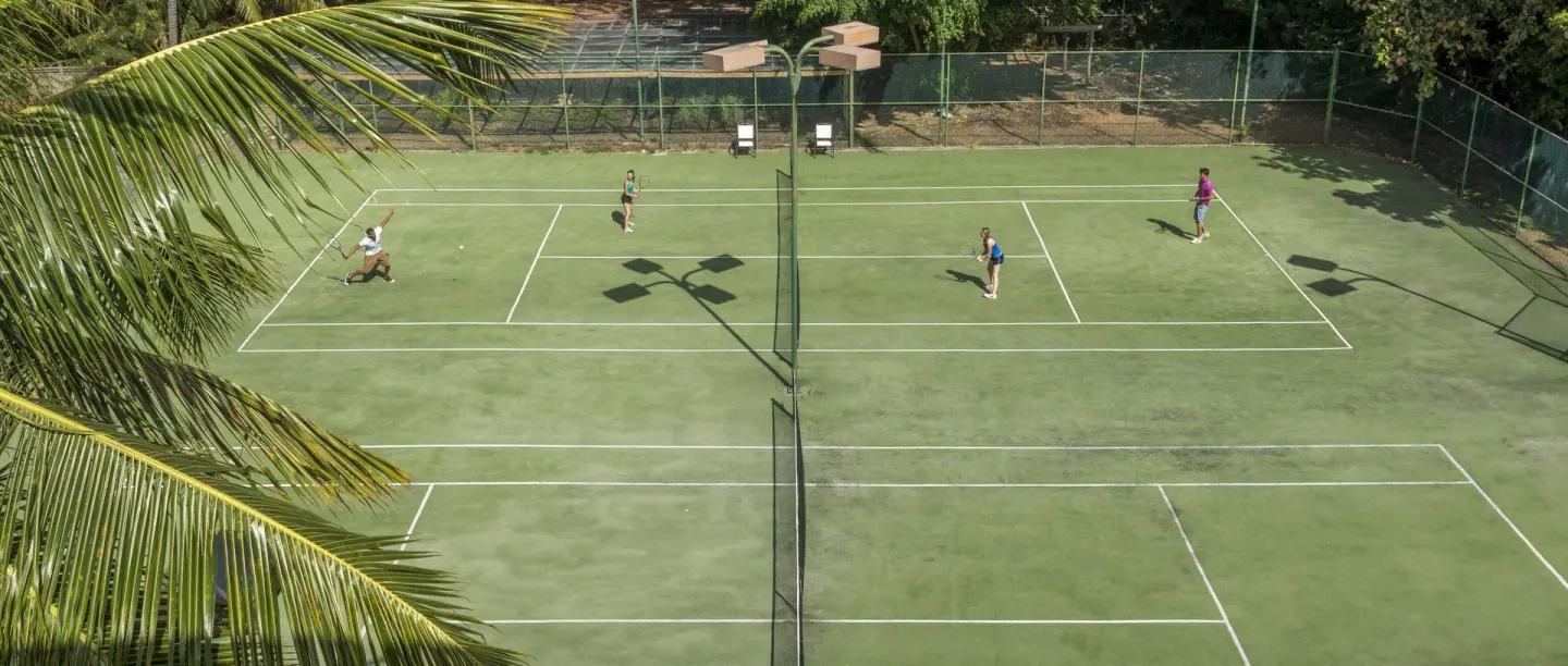 Tennis courts with players and palm trees at Divi Southwinds Beach Resort.