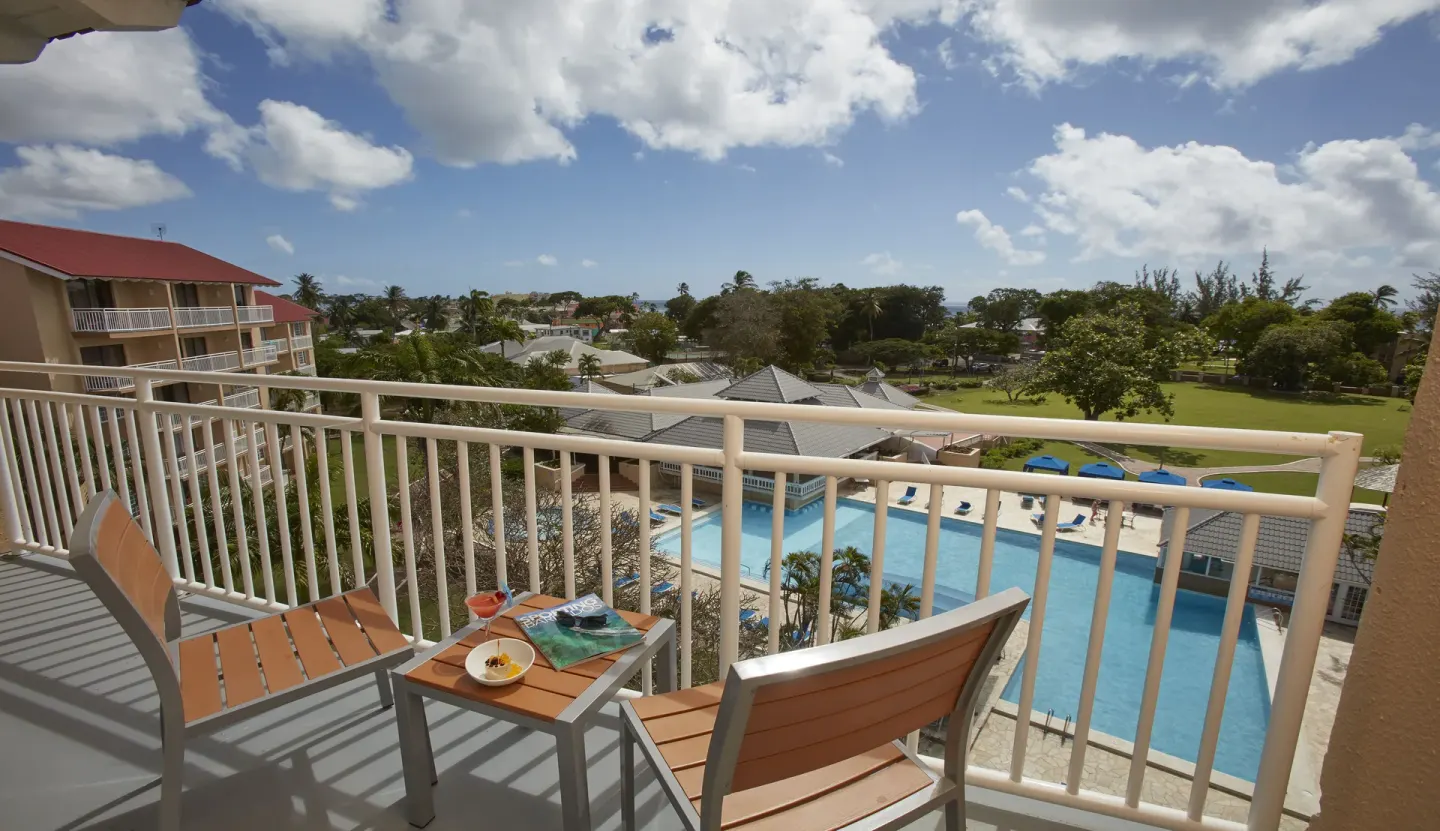 Pool view balcony with chairs and table at Divi Southwinds Beach Resort.