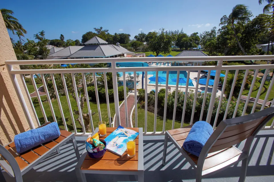 Two-bedroom suite balcony with chairs overlooking the pool at Divi Southwinds Beach Resort.