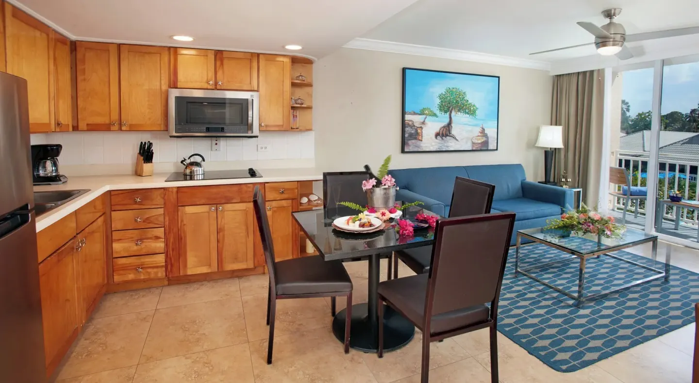 Open kitchen, dining area, sofa, and balcony doors in a suite at Divi Southwinds Beach Resort.