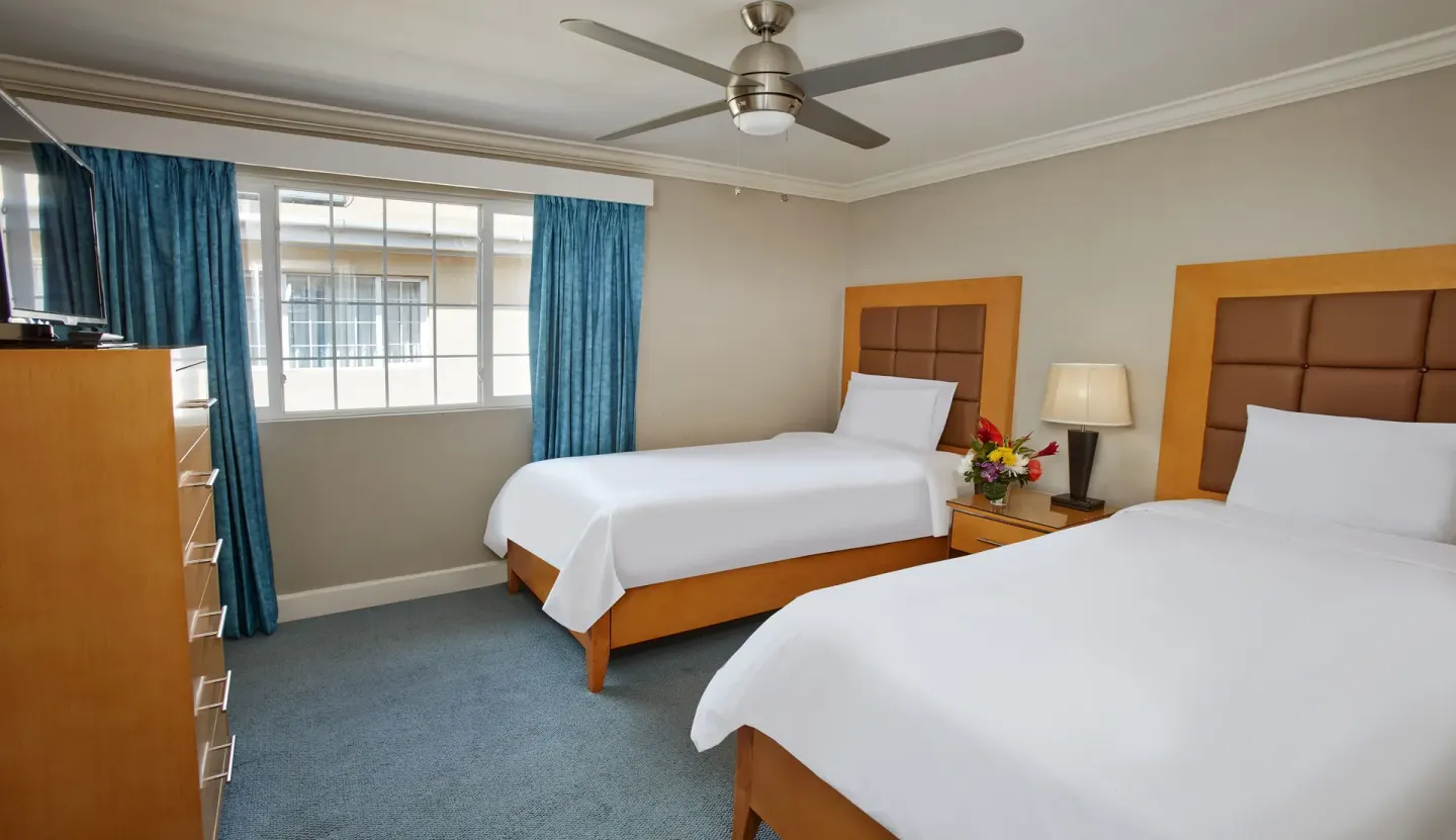 Two-bed bedroom with blue curtains in a two-bedroom suite at Divi Southwinds Beach Resort.