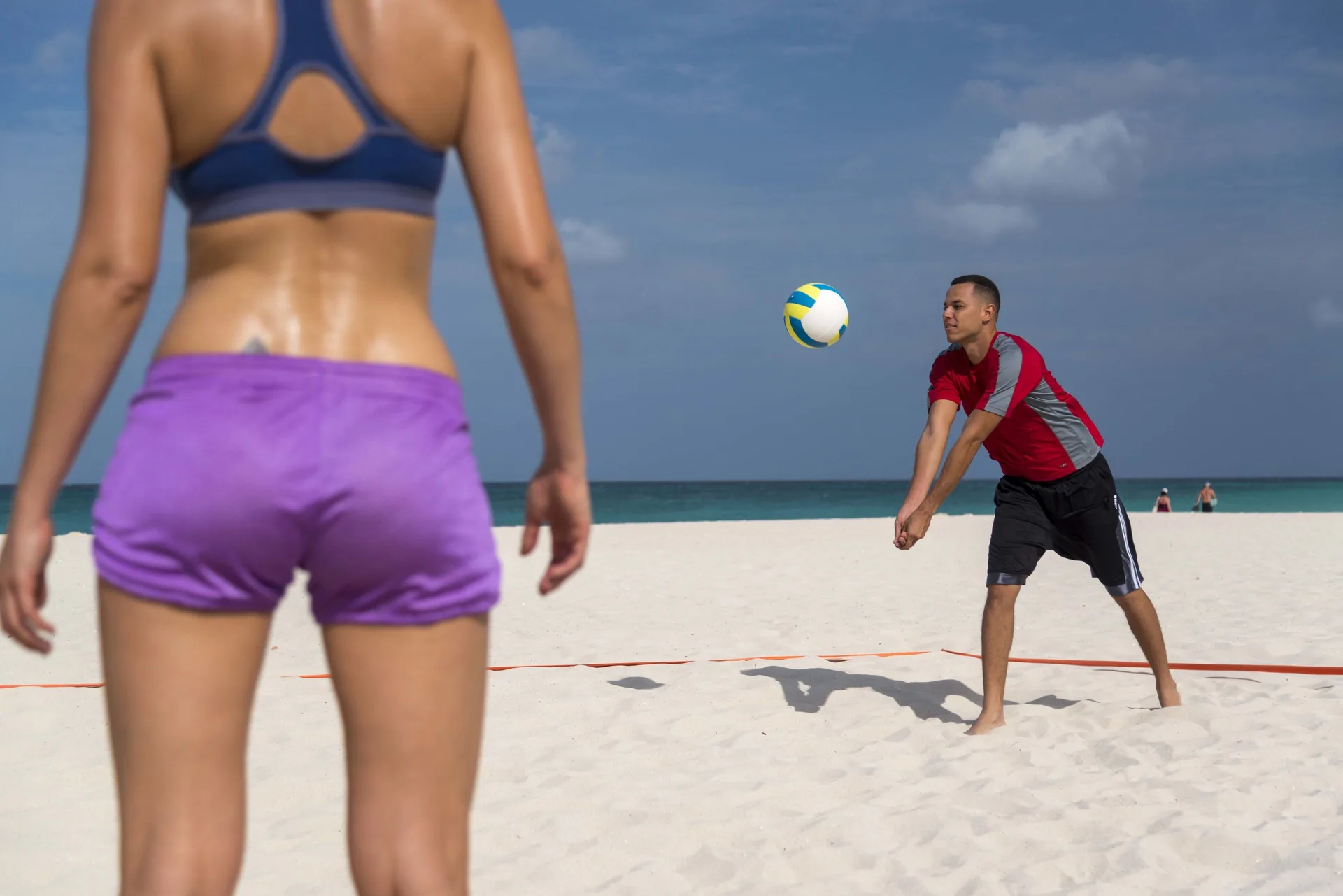 Guests play beach volleyball by the ocean at Divi Village Golf & Beach Resort.
