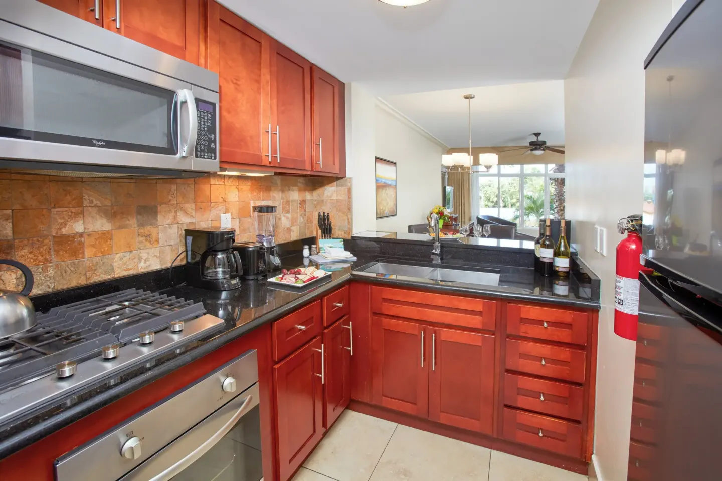 Compact suite kitchen at Divi Village Golf & Beach Resort with red cabinets and black counters.