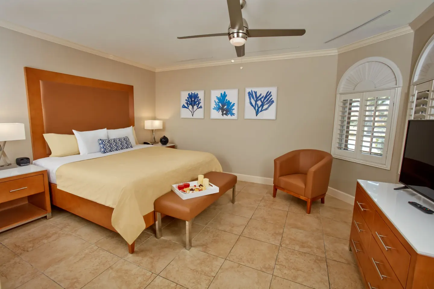 Guest room with king bed, coral artwork and armchair at Divi Village Golf & Beach Resort.