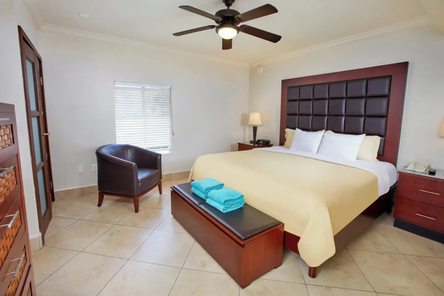 Guest room with king bed, bench and leather chair at Divi Village Golf & Beach Resort.