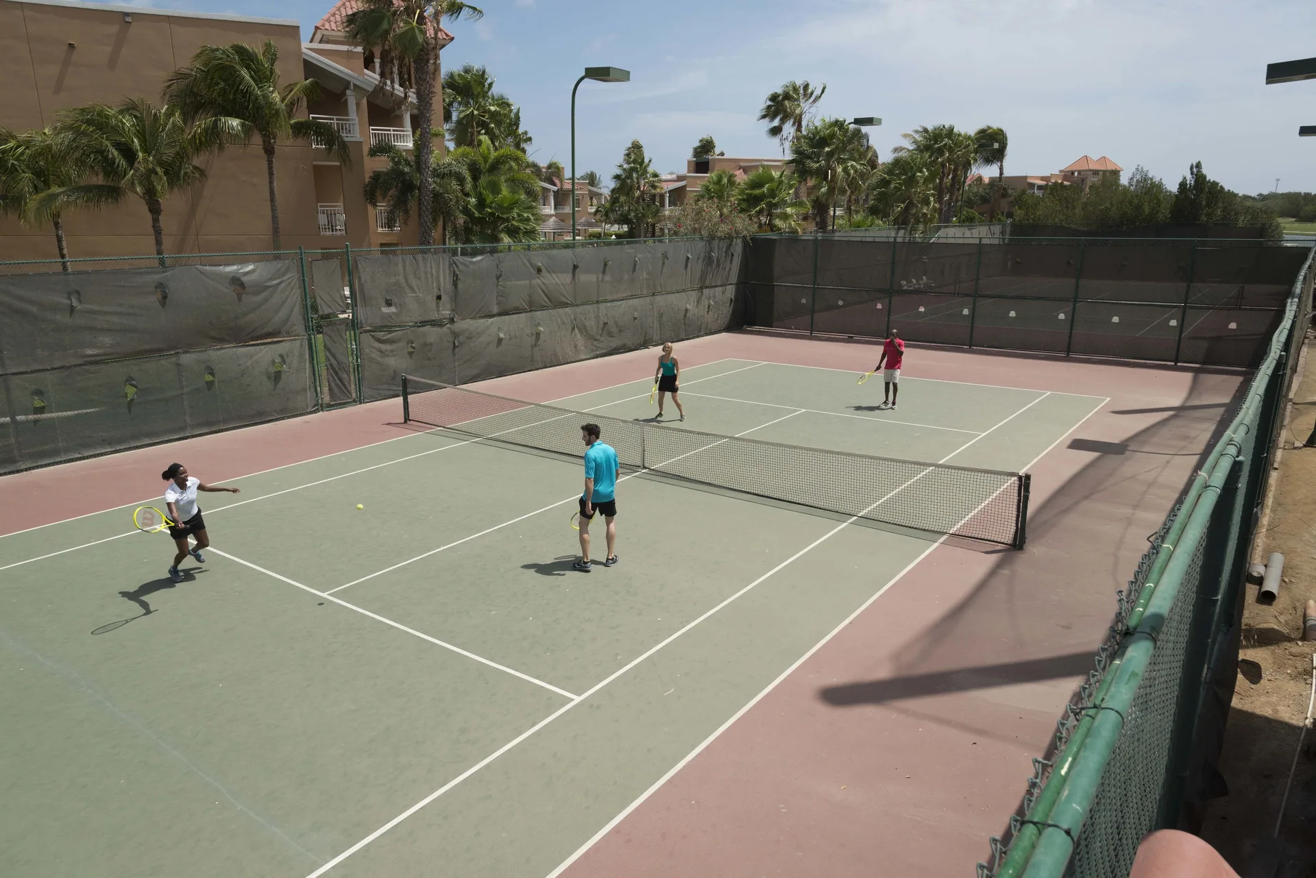 Guests playing tennis on an outdoor court at Divi Village Golf & Beach Resort.