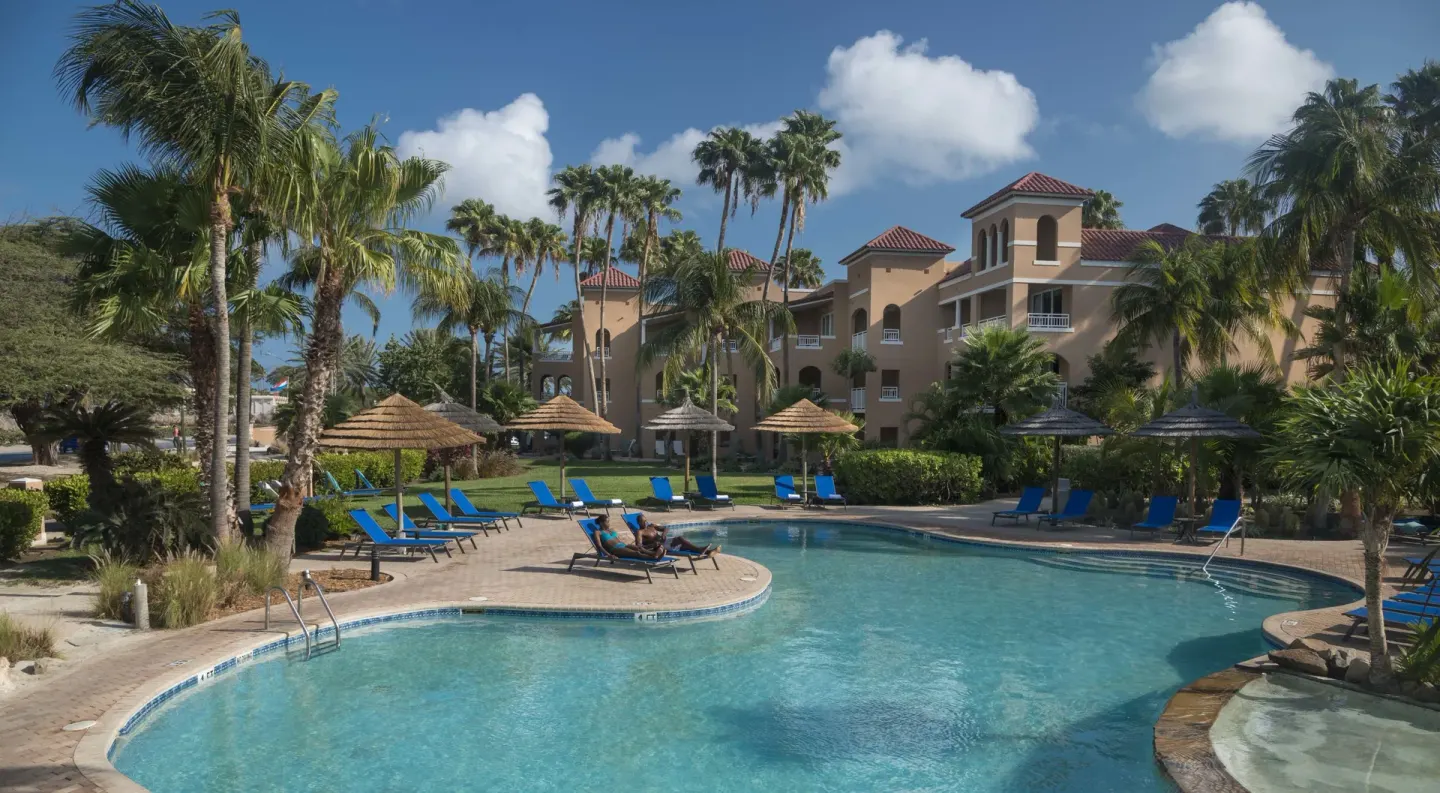 Resort pool with palm trees and lounge chairs at Divi Village Golf & Beach Resort.