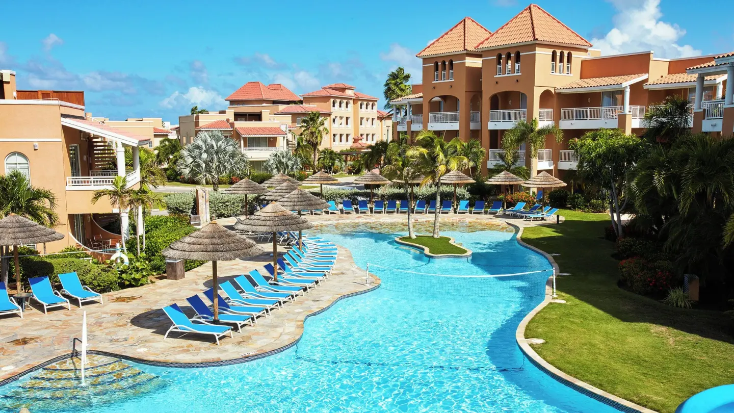Pool courtyard with blue loungers and tan resort buildings at Divi Village Golf & Beach Resort.