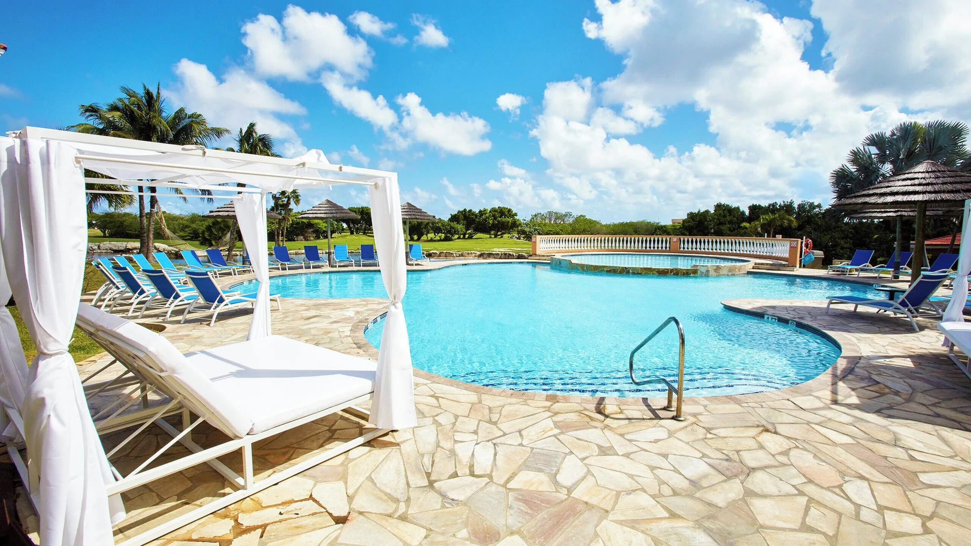 Pool deck with white cabana and blue lounge chairs at Divi Village Golf & Beach Resort.