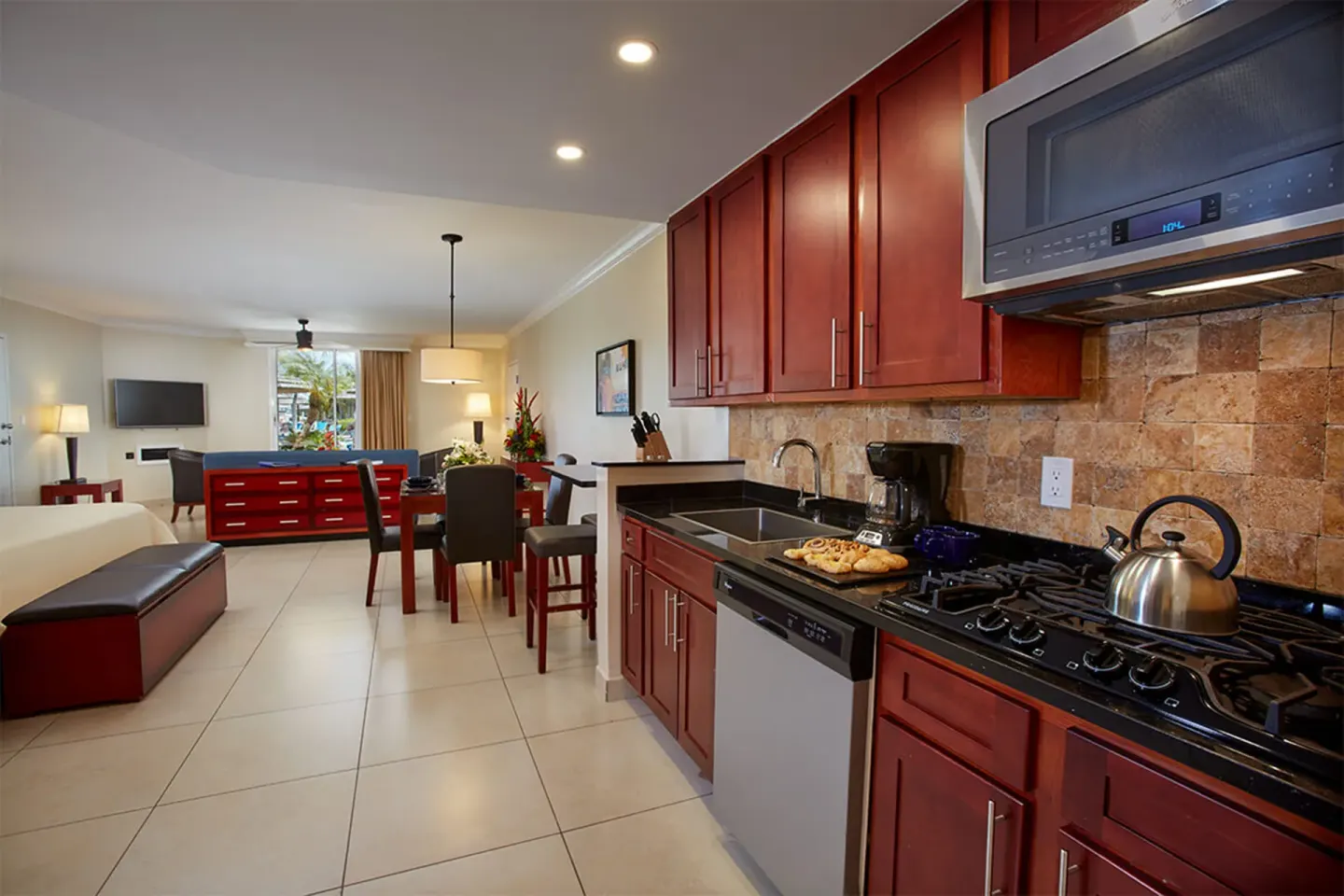 Suite kitchen and living area at Divi Village Golf & Beach Resort with red cabinets and dining space.