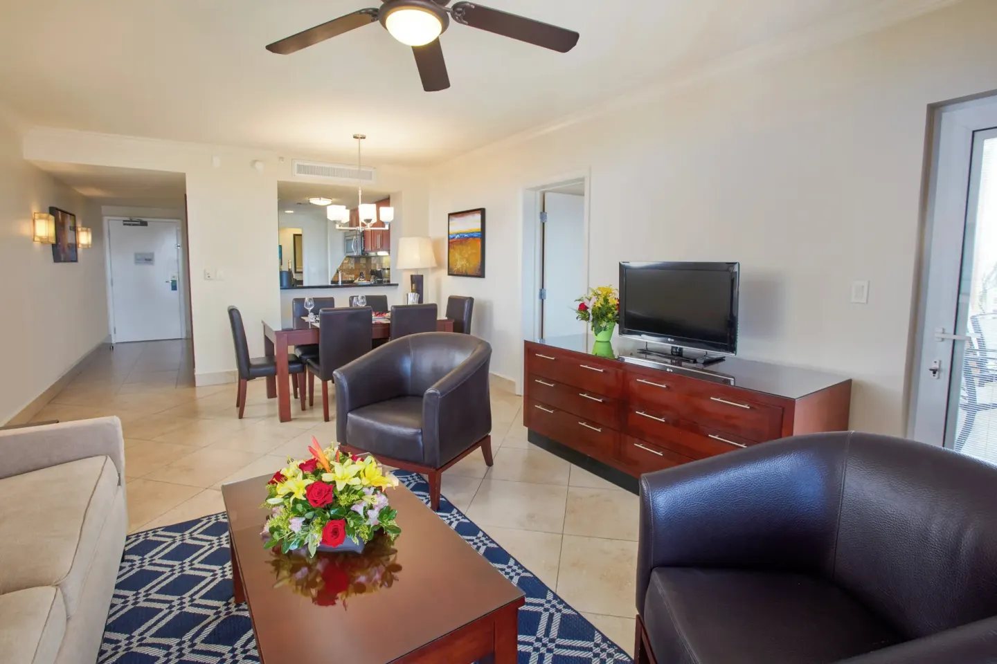 Suite living room at Divi Village Golf & Beach Resort with TV console, dining table, and balcony door.