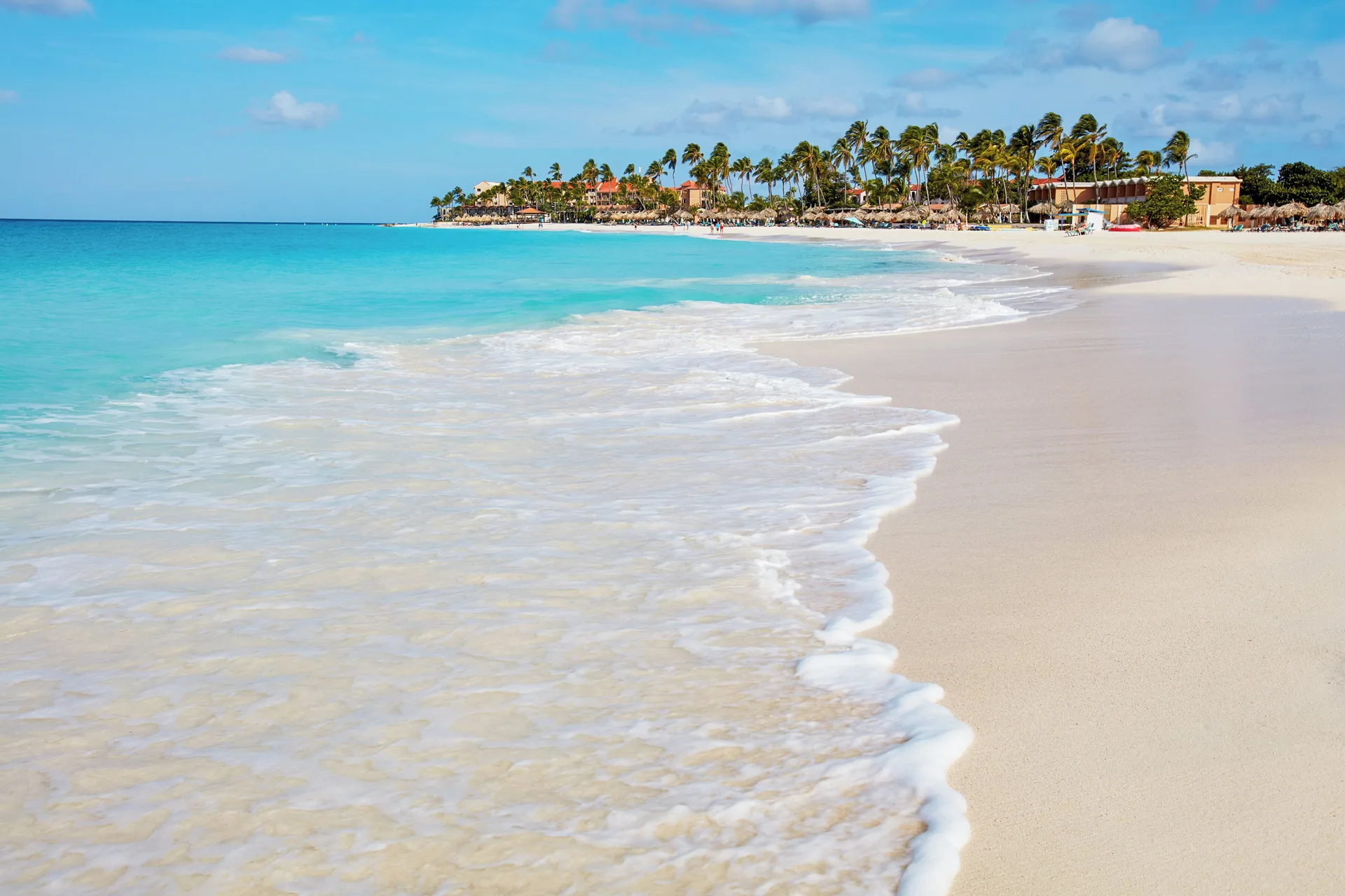 Wide white-sand beach and turquoise surf at Divi Village Golf & Beach Resort.