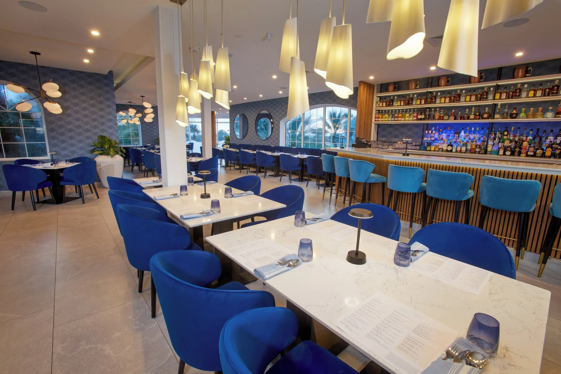 Blue chairs, white tables and a long bar inside a restaurant at Divi Village Golf & Beach Resort.