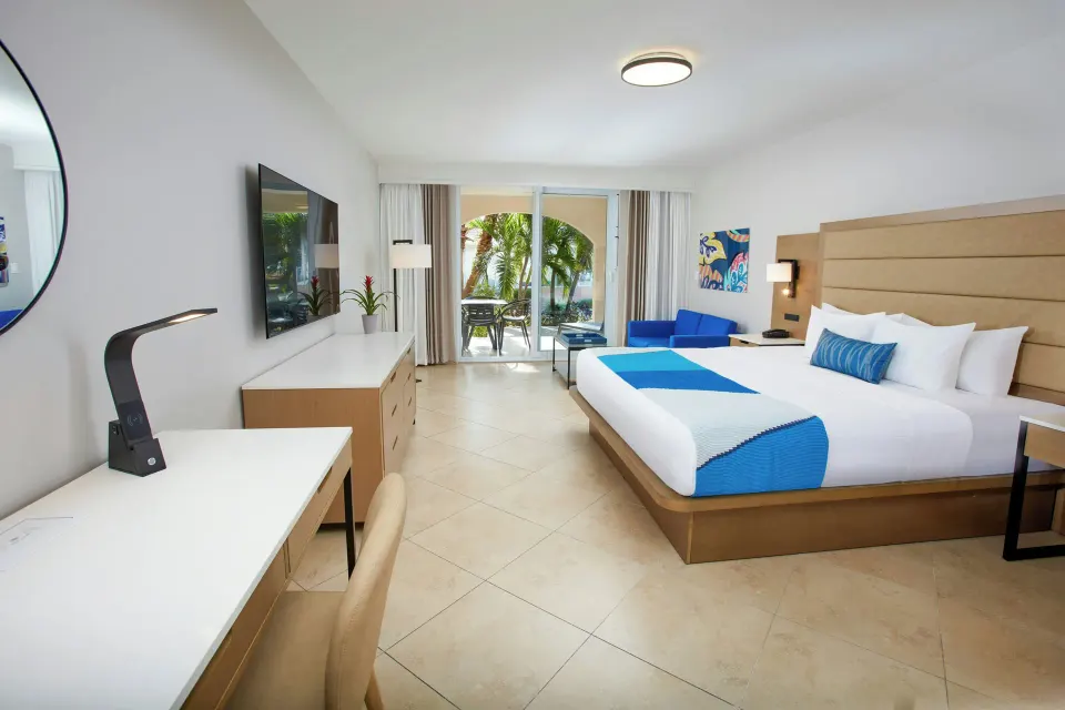 One Bedroom Suite king bedroom with blue accents at Divi Village Golf & Beach Resort.