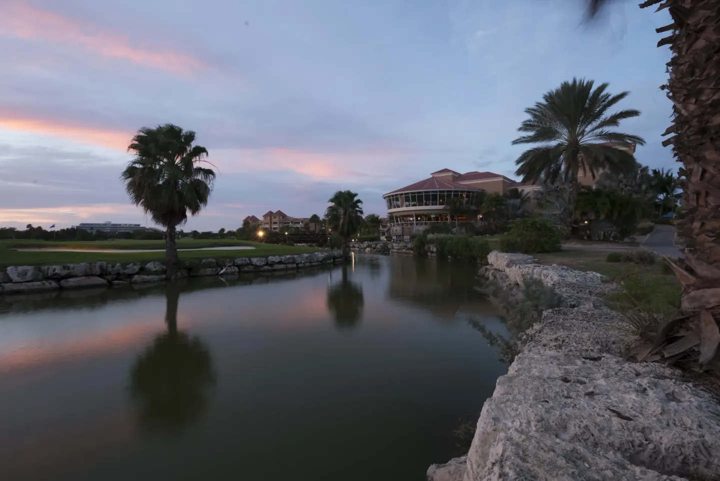Lagoon with palms, rocks, and resort buildings at dusk at Divi Village Villas.