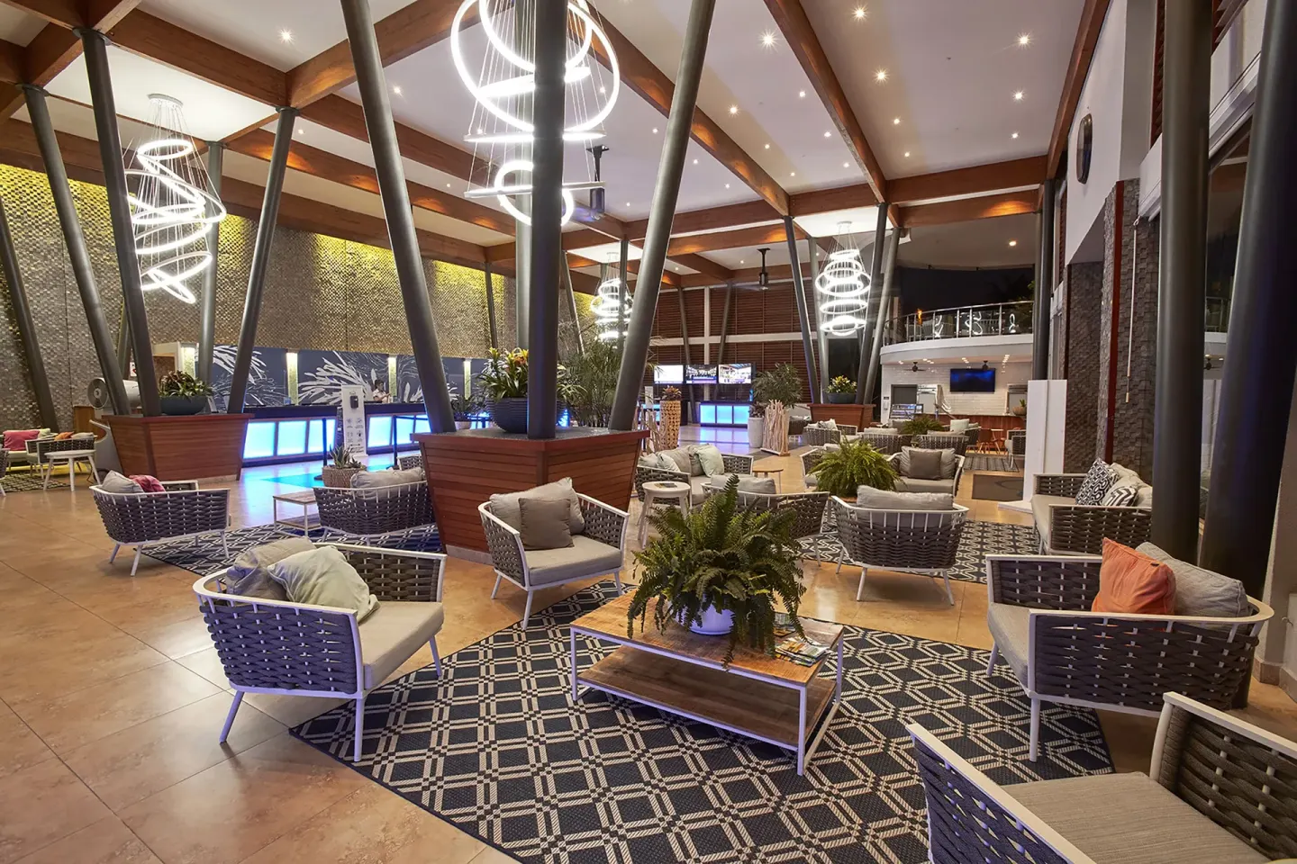 Lobby lounge with woven chairs, patterned rugs, plants, and reception area at Divi Village Villas.