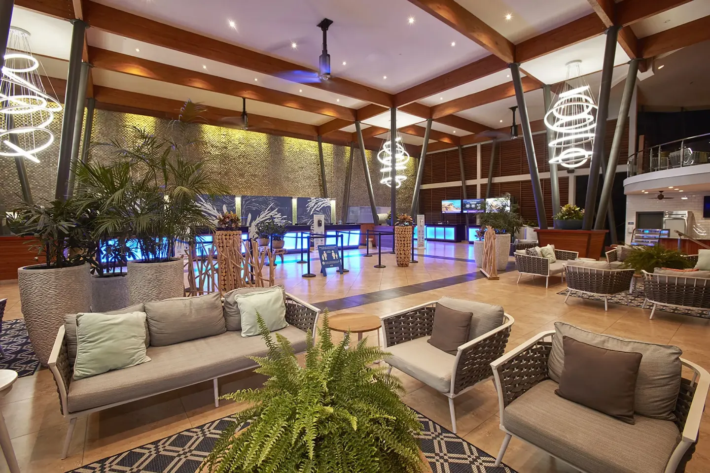 Lobby lounge seating with plants, rugs, reception desks, and pendant lights at Divi Village Villas.