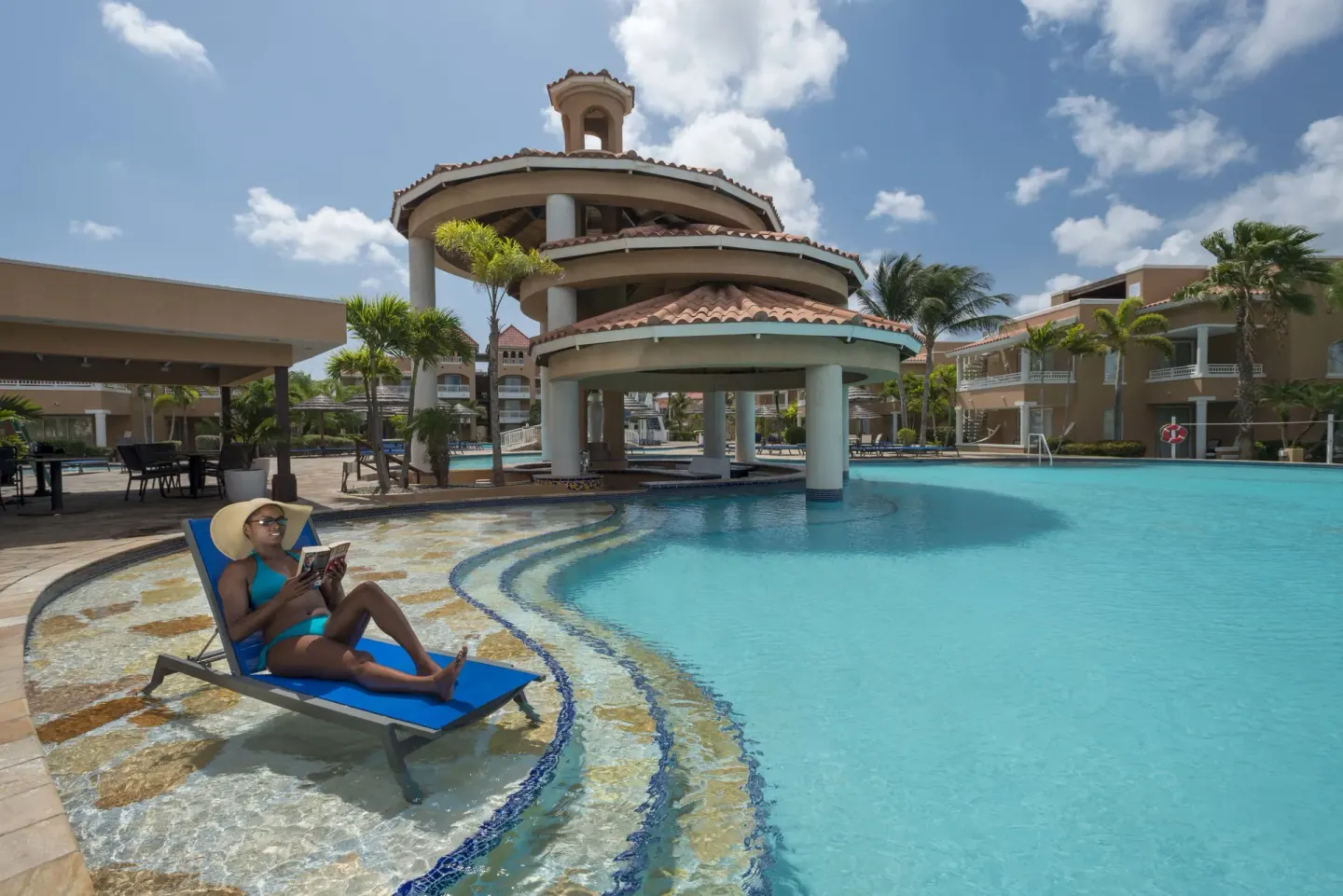 Guest relaxing on a blue lounger beside the pool pavilion at Divi Village Villas.
