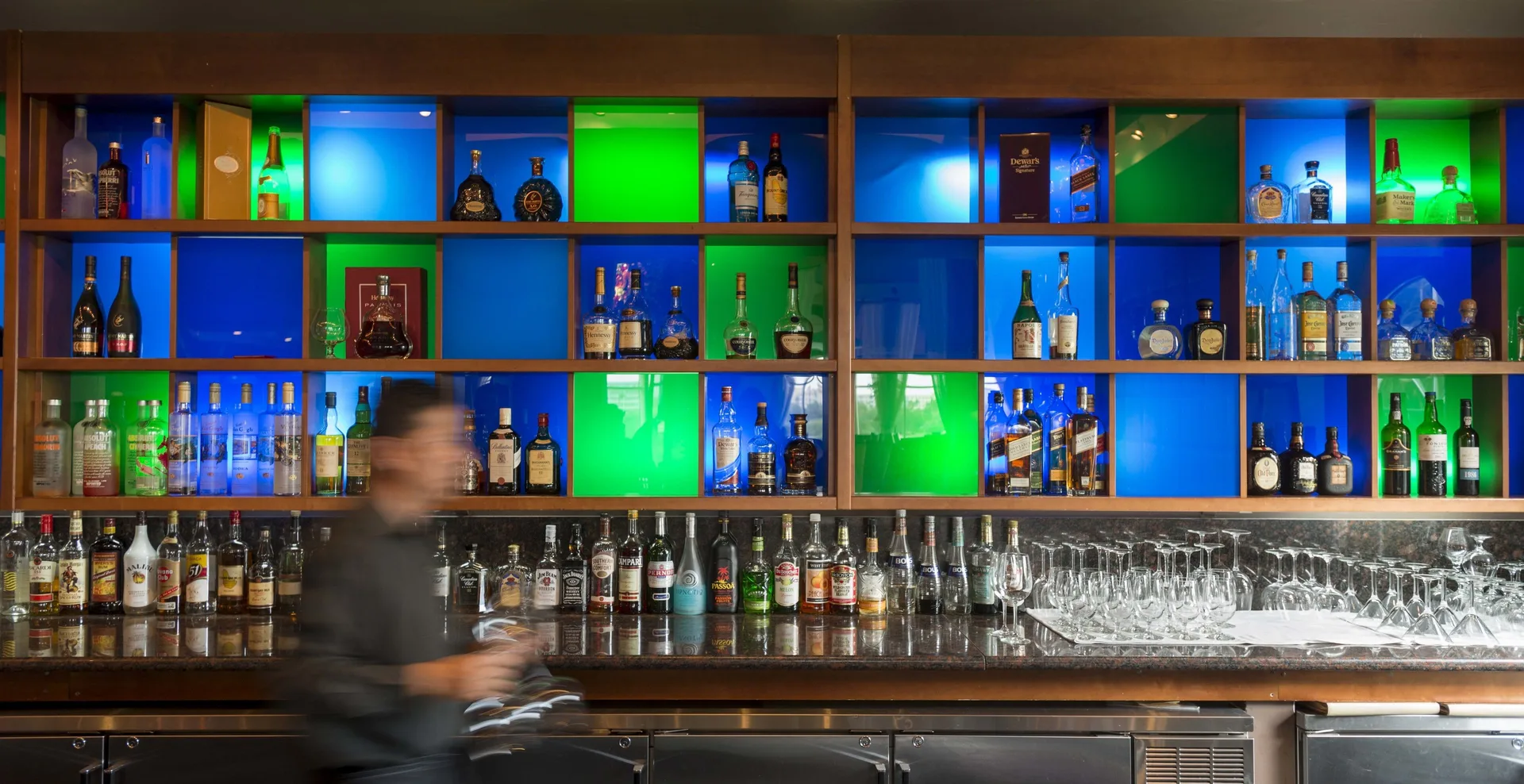 Bar shelves with bottles, glassware, and colored panels at Divi Village Villas.