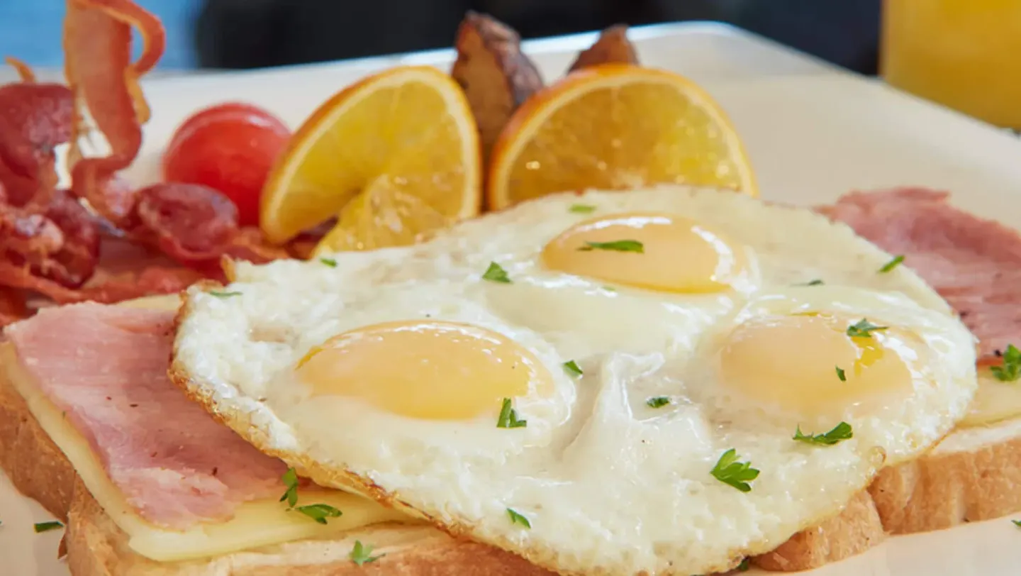 Close-up of a breakfast plate with eggs, ham, toast, and fruit at Divi Village Villas.