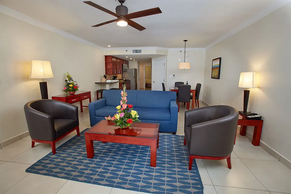 One-bedroom suite living area with sofa, chairs, dining table and kitchen at Divi Village Villas.