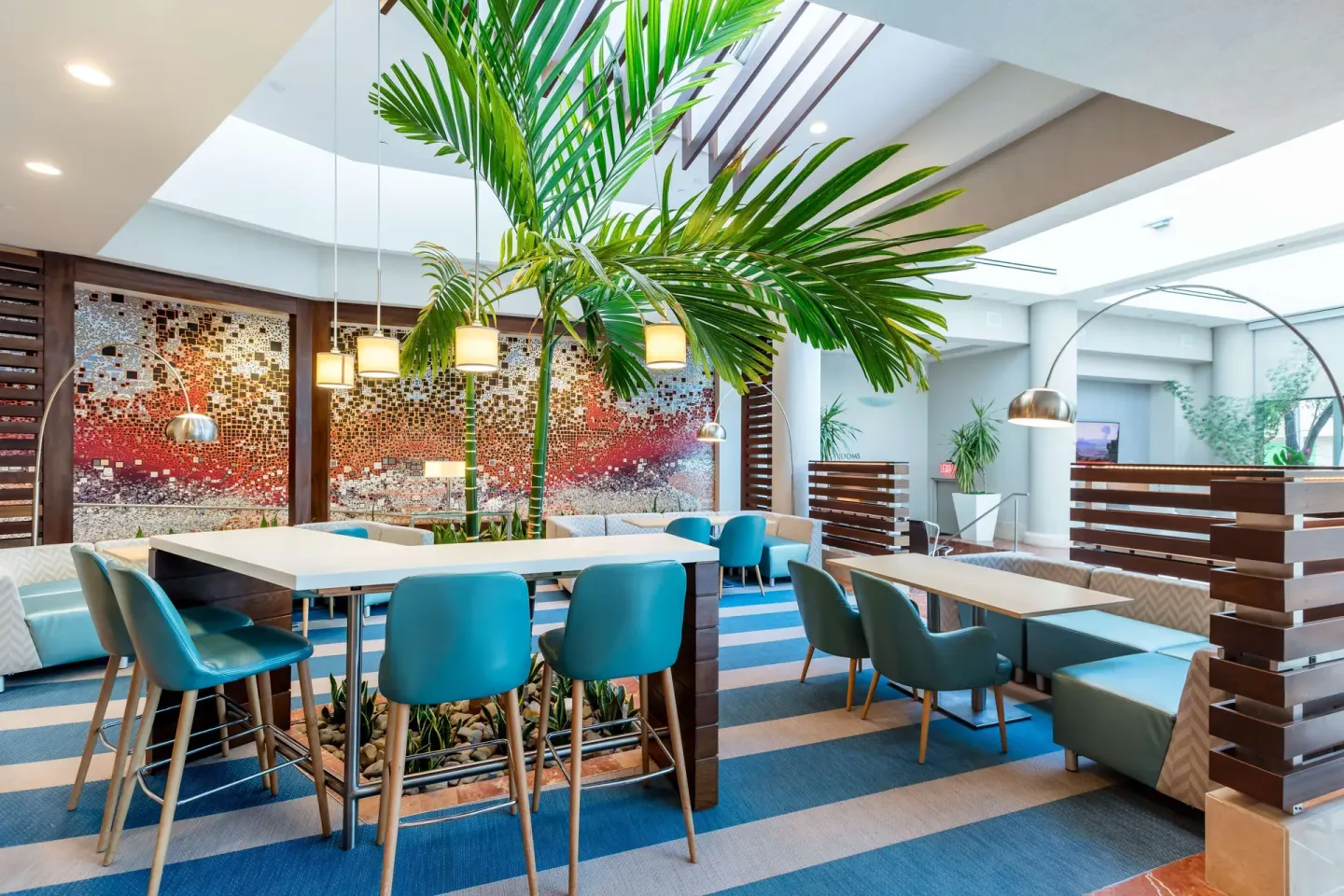 Bright lobby lounge with teal chairs and tropical plants at DoubleTree San Juan.