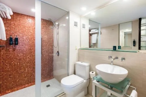 Bathroom vanity, toilet, and glass shower with red tile at DoubleTree San Juan.