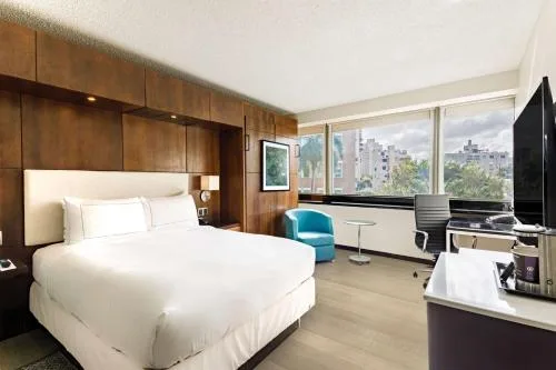 Murphy Garden View room with white bed, beverage counter, desk, and large windows at DoubleTree San Juan.