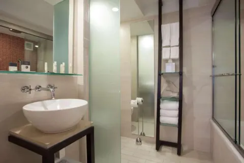 Corner Room bathroom at DoubleTree San Juan with vessel sink, glass shelving and tub-shower.