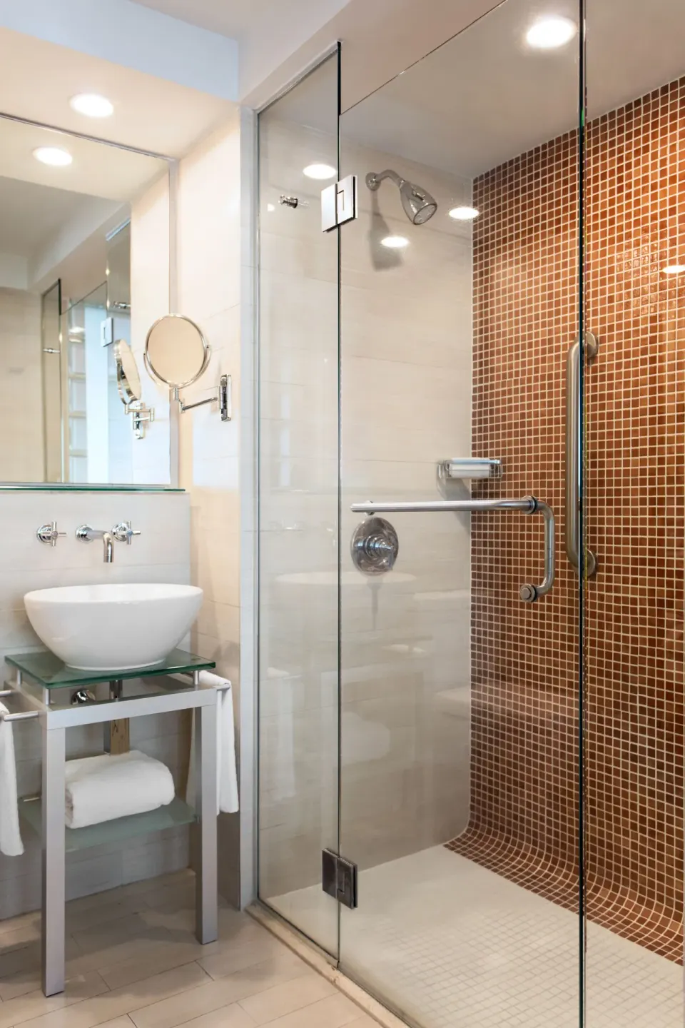 Bathroom with glass shower, vessel sink, mirror, and brown tile accent at DoubleTree San Juan.