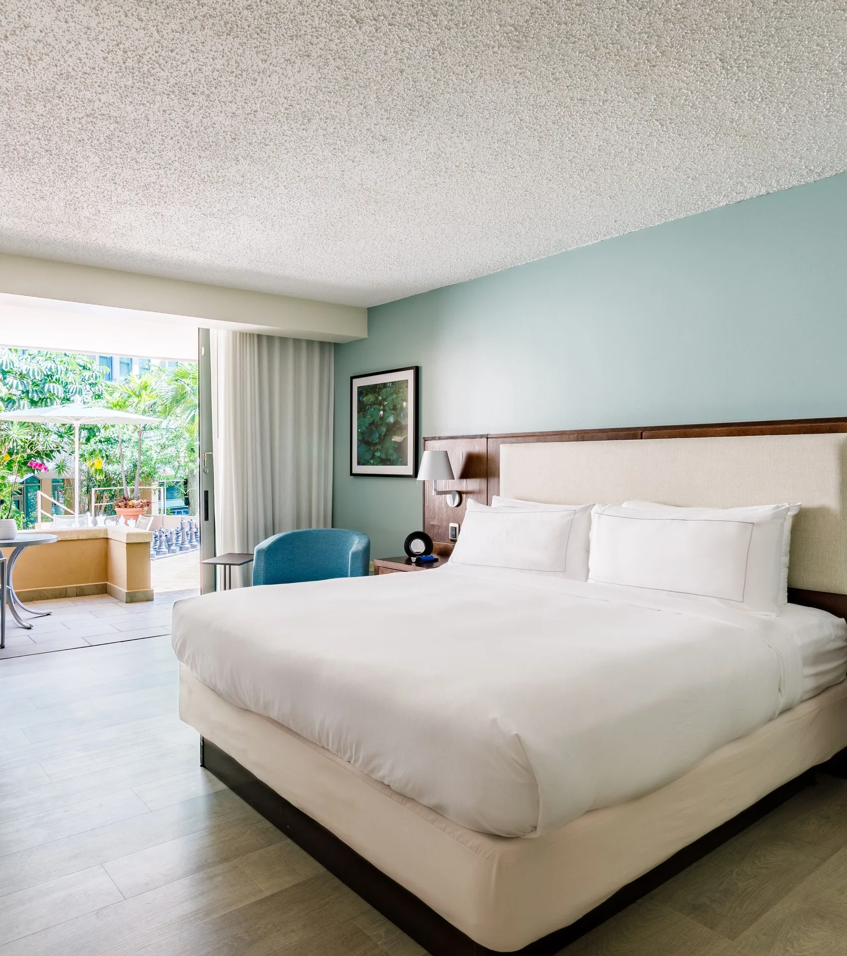 Deluxe balcony room with one bed, blue chair, and open balcony doors at DoubleTree San Juan.