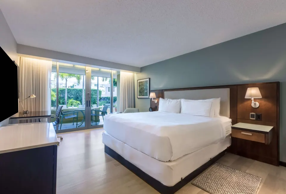 Deluxe balcony room with one bed, glass doors, and patio seating at DoubleTree San Juan.