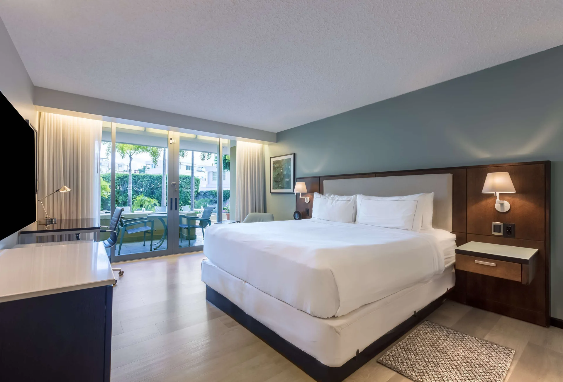 Deluxe balcony room with one bed, glass doors, and patio seating at DoubleTree San Juan.