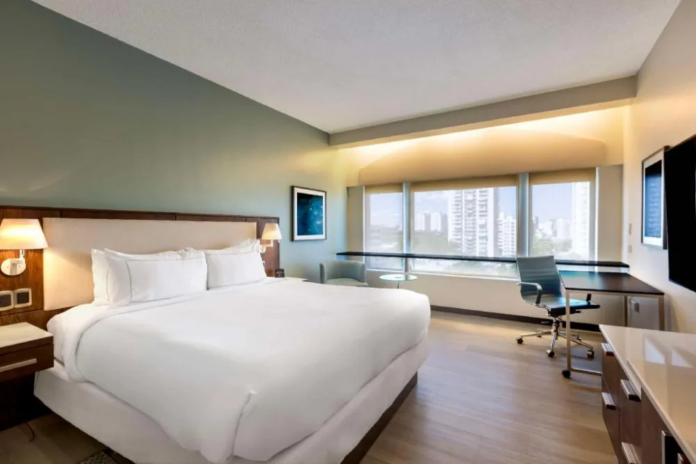 Higher floor king guest room with bed, desk and city-facing windows at DoubleTree San Juan.
