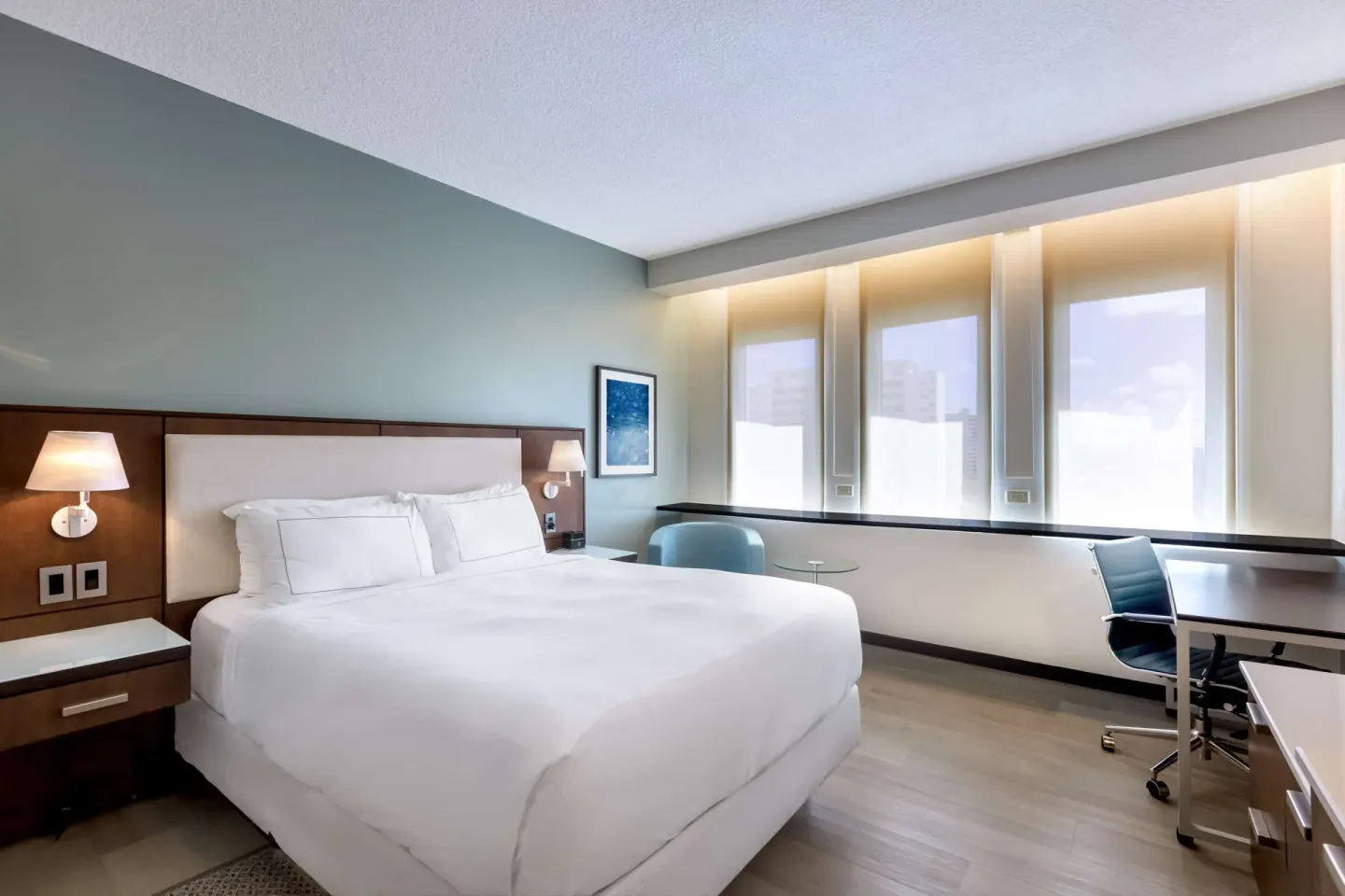 Standard Room at DoubleTree San Juan with a king bed, bedside lamps, desk, and three tall windows.