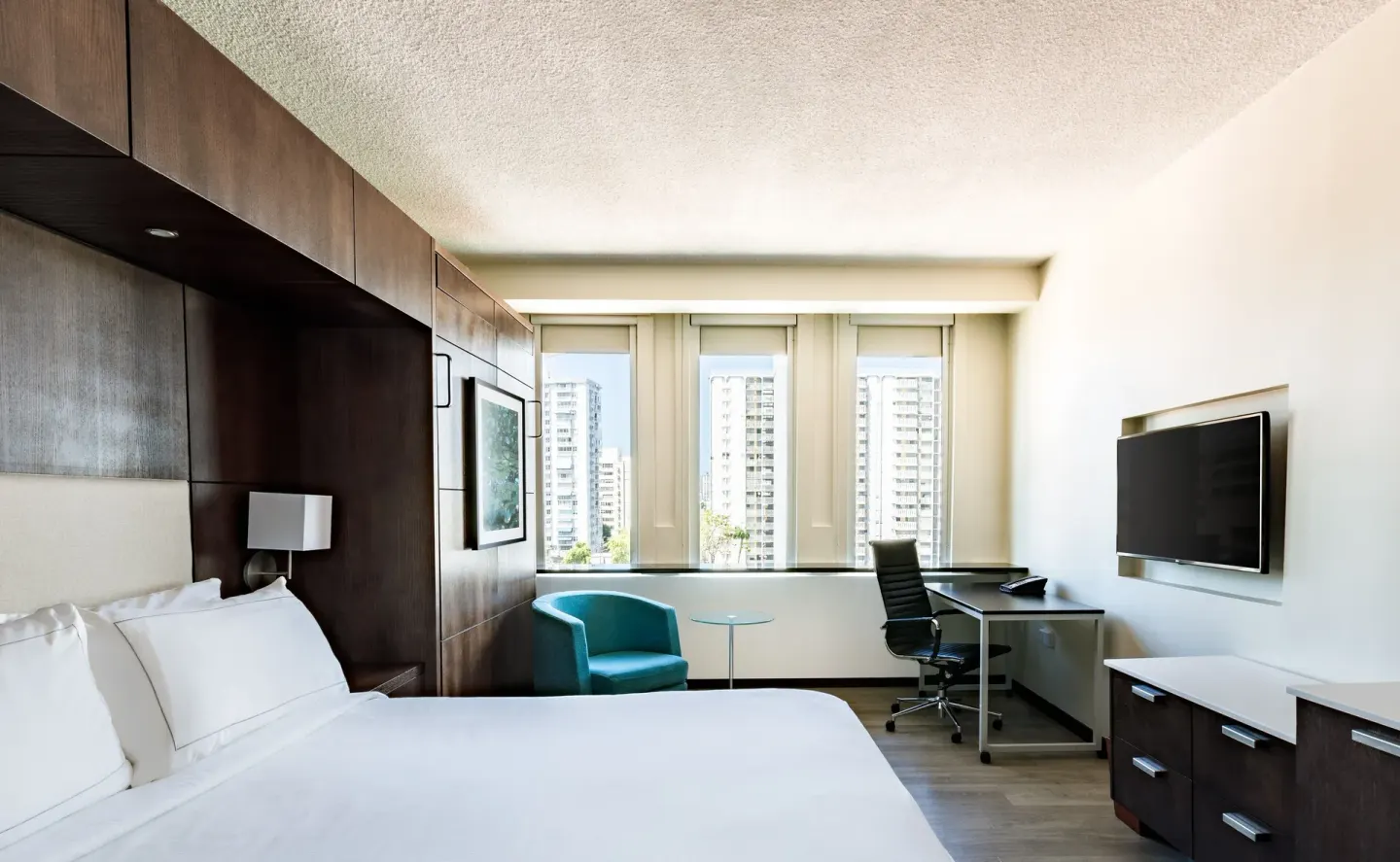 Standard Room at DoubleTree San Juan with a king bed, wall TV, desk, and city-facing windows.
