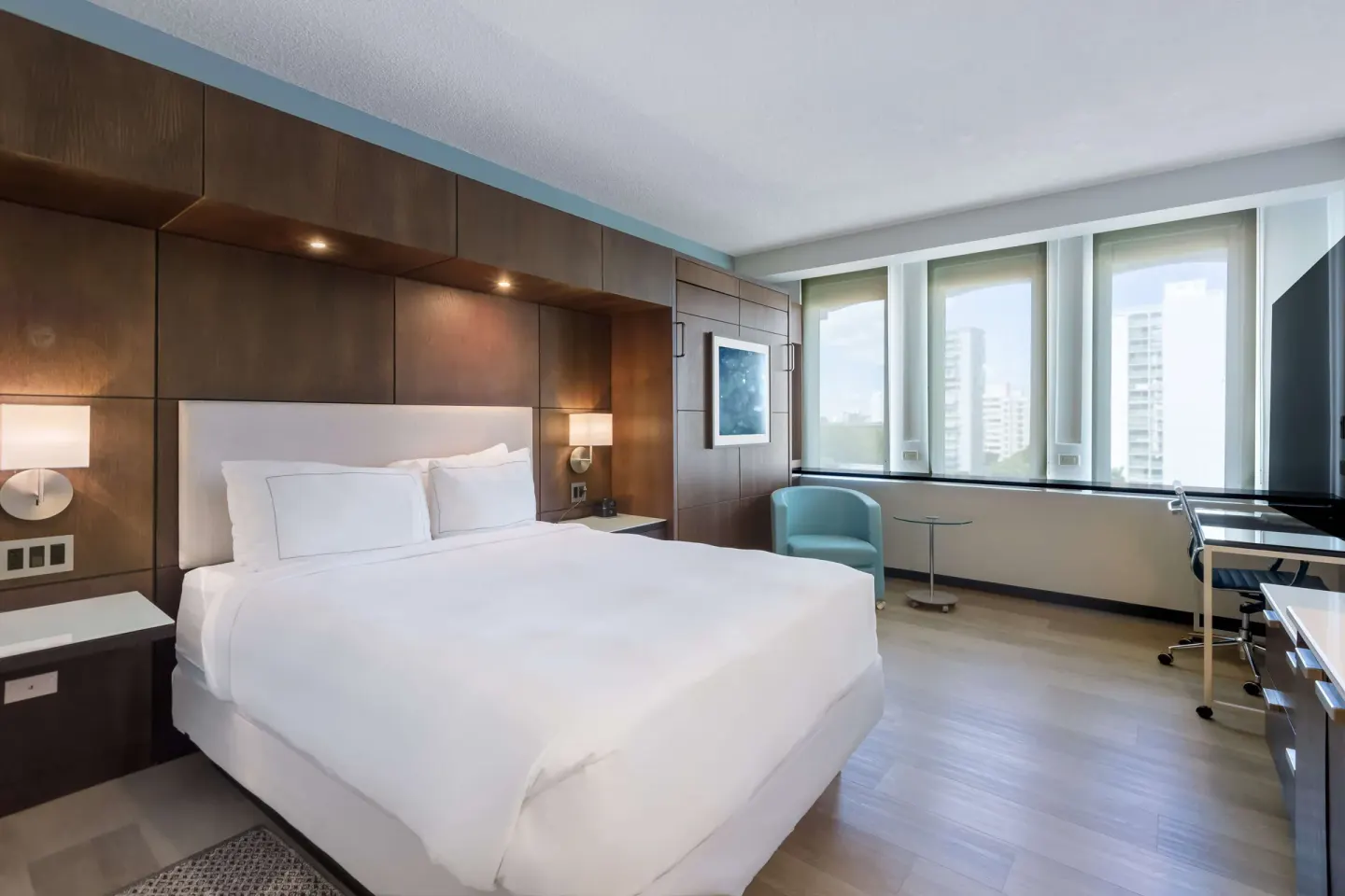 Standard Room at DoubleTree San Juan with one white bed, large windows, seating, and a desk.