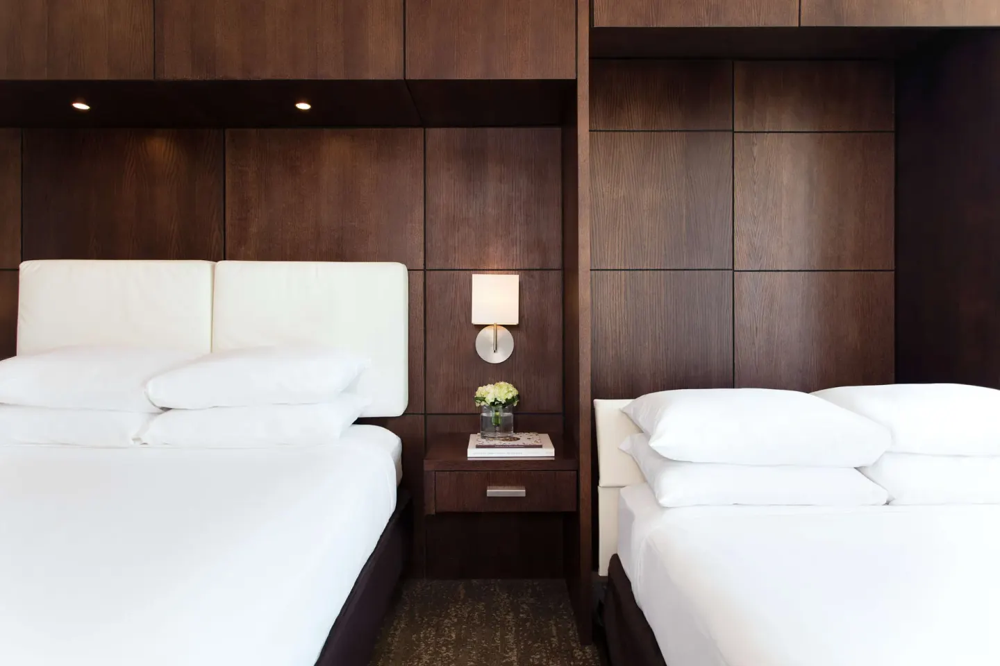 Two beds in a Standard Room at DoubleTree San Juan with dark wood paneling and a center nightstand.