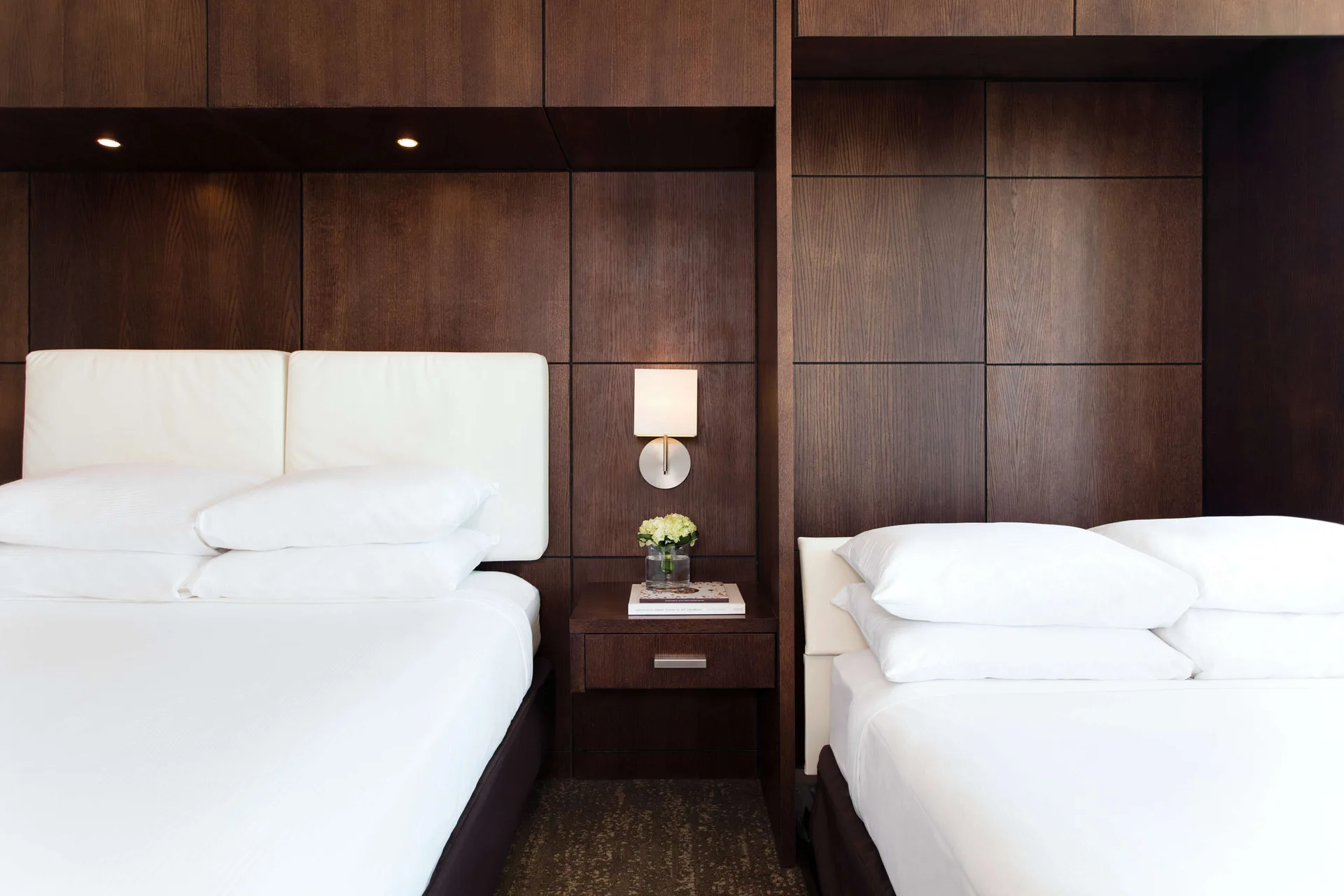 Two beds in a Standard Room at DoubleTree San Juan with dark wood paneling and a center nightstand.