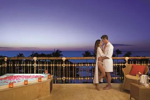 Couple on a balcony beside a flower-filled hot tub at Dreams Riviera Cancun Resort & Spa.