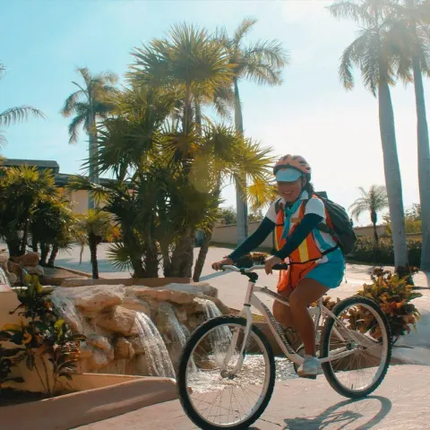 Cyclist riding past palms and a water feature at Dreams Riviera Cancun Resort & Spa.