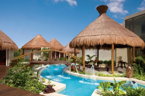 Spa pool with thatched cabanas and water features at Dreams Riviera Cancun Resort & Spa.
