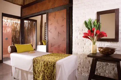Spa treatment room with massage table and floral arrangement at Dreams Riviera Cancun Resort & Spa.