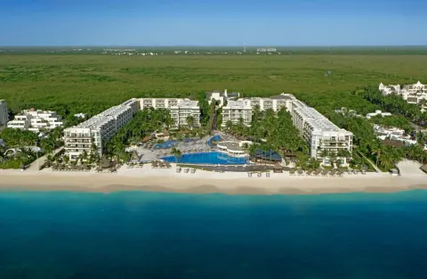 Wide aerial view of Dreams Riviera Cancun Resort & Spa with pools, beach, and surrounding greenery.
