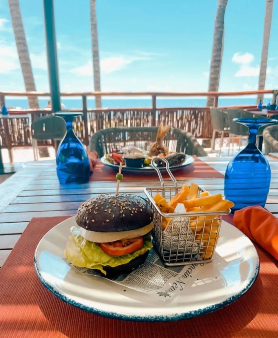 Burger and fries on an oceanview restaurant table at Dreams Riviera Cancun Resort & Spa.