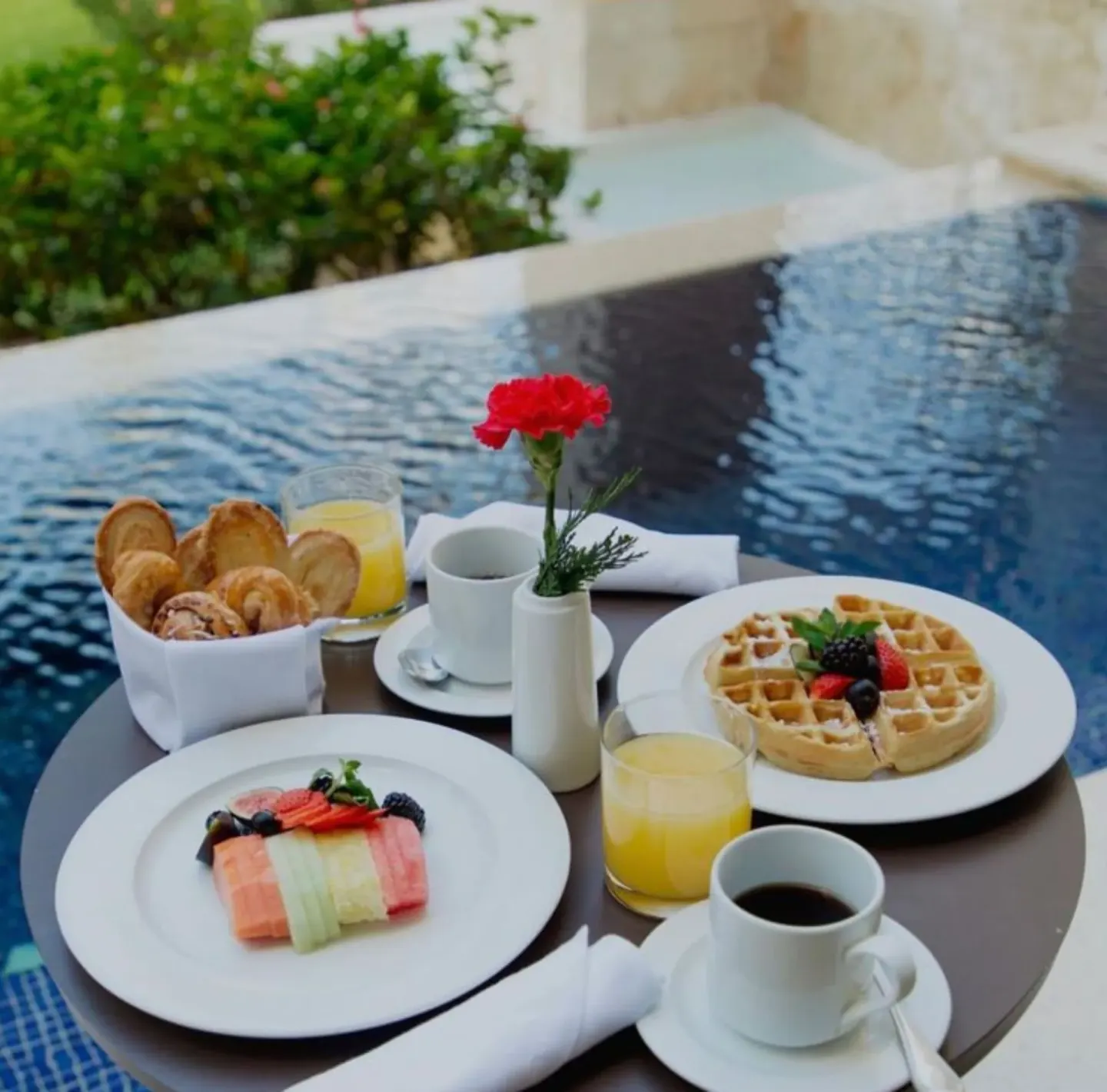 Breakfast plates beside a pool at Dreams Riviera Cancun Resort & Spa.