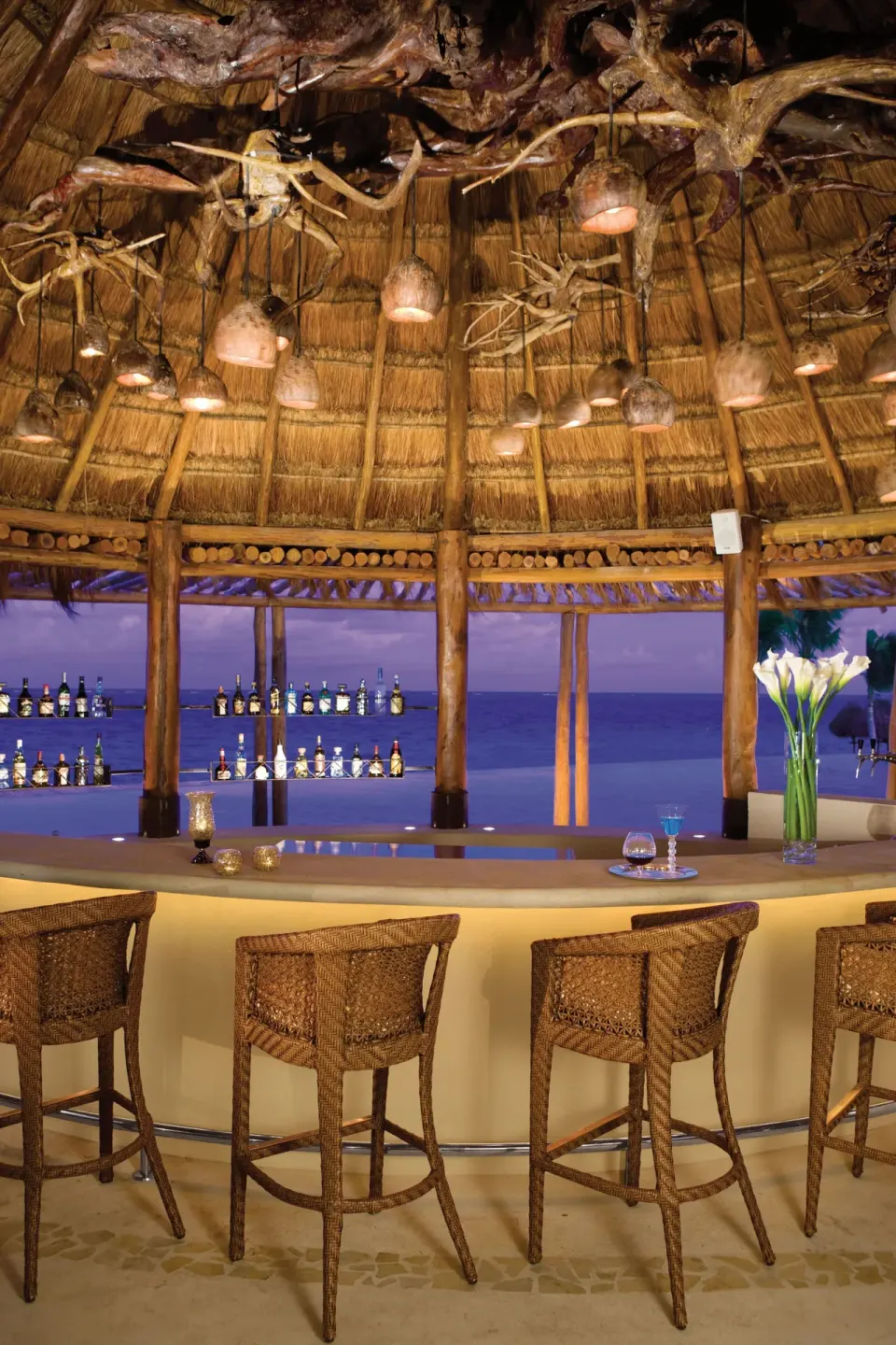 Thatched beach bar with wicker stools at Dreams Riviera Cancun Resort & Spa.
