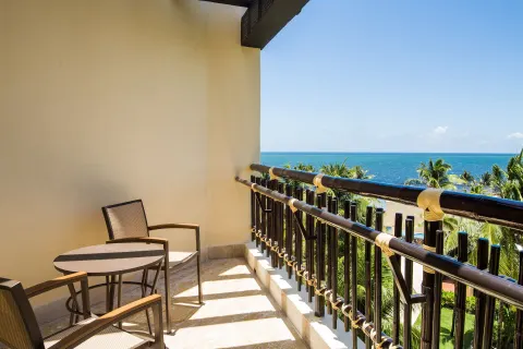 Premium Deluxe Ocean View balcony at Dreams Riviera Cancun Resort & Spa with chairs, table, palms, and sea.