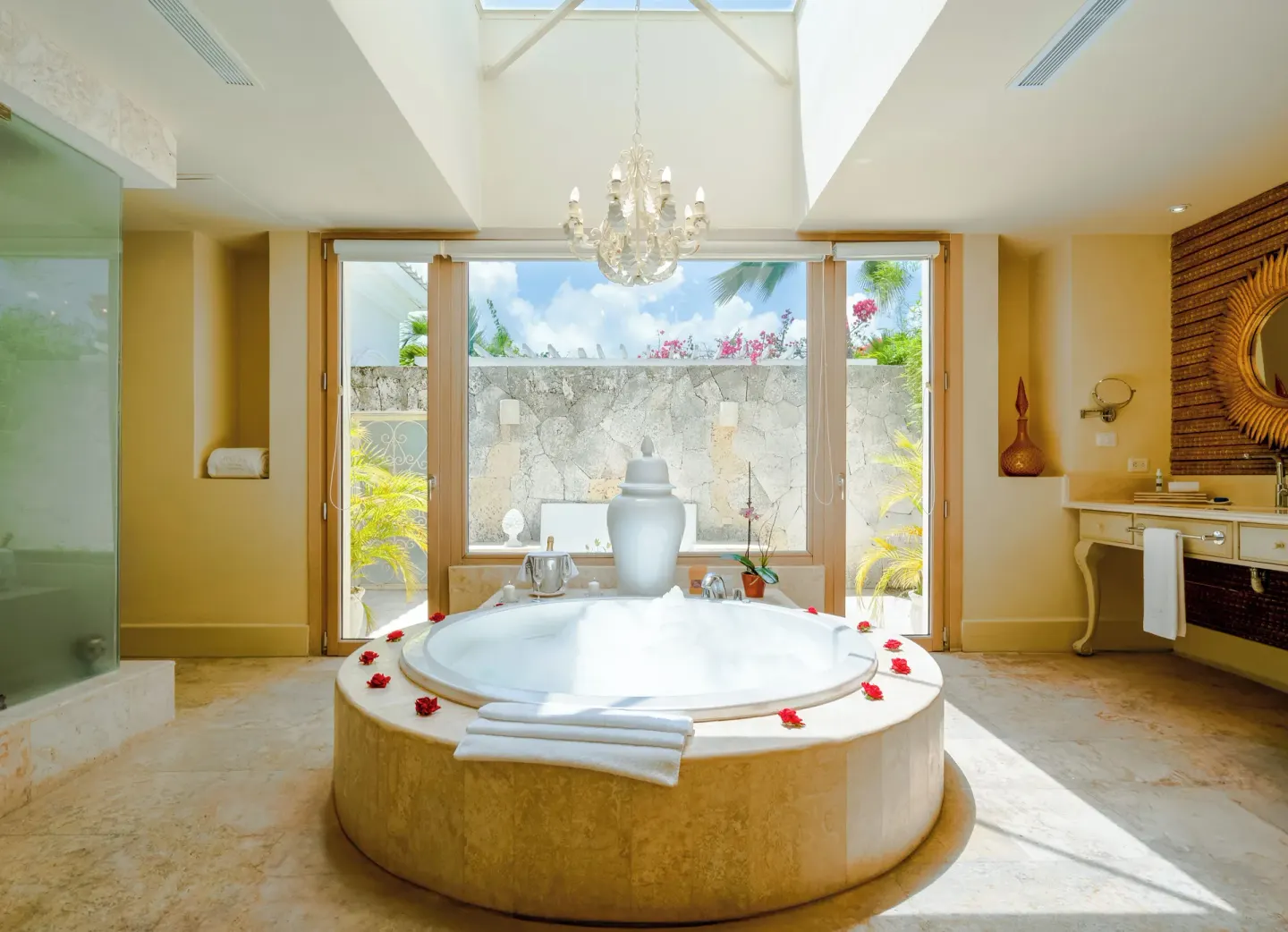 Large bathroom with round soaking tub, chandelier, and garden-facing windows at Eden Roc Cap Cana.