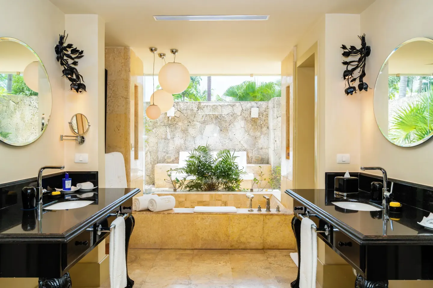 Bathroom with twin vanities, soaking tub, and outdoor stone-walled area at Eden Roc Cap Cana.